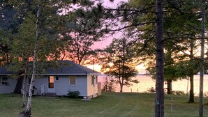 Una casa con un pequeño patio y vista a un lago al atardecer.