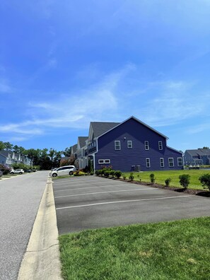 A residential street with a large blue house, a parking lot, and a clear blue sky. - Delaware Dreaming (Selbyville)