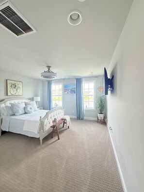 A bedroom with a bed, bedside table, lamp, window with curtains, and a ceiling fan. - Delaware Dreaming (Selbyville)