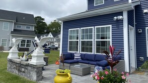 A blue house with a porch, a blue sofa, and a yellow planter with flowers. - Delaware Dreaming (Selbyville)