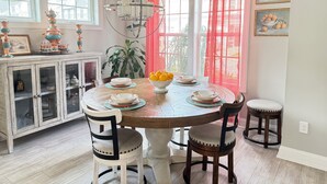 A dining area with a round wooden table, four chairs, a chandelier, and a cabinet with glass doors. - Delaware Dreaming (Selbyville)