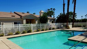 A clear swimming pool with a white fence, palm trees, and a building with a tiled roof. - Modern PGA West 2 bd/2ba with views, pool/spa (La Quinta)