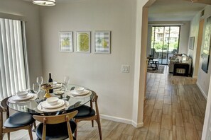 A dining area with a glass table, chairs, and a view of a patio with a sofa and a table. - Modern PGA West 2 bd/2ba with views, pool/spa (La Quinta)