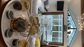 A dining table with a tray of desserts, including clotted cream and scones, in a modern interior with a view of the outdoors.