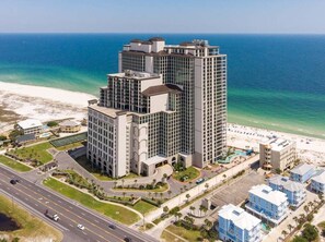 Ein Hochhaus-Hotel mit mehreren Etagen, Blick auf den Strand und einem Parkplatz.