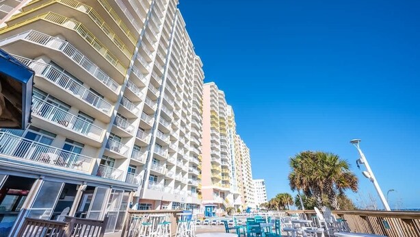A high-rise hotel with multiple balconies, outdoor seating, and a clear blue sky. - Bay Watch 503 Direct Oceanfront w/ Tiki Bar, Pools (North Myrtle Beach)