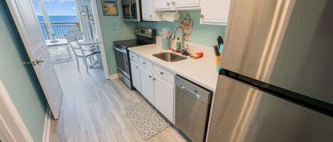 A kitchen with white cabinets, stainless steel appliances, and a view to the outside.