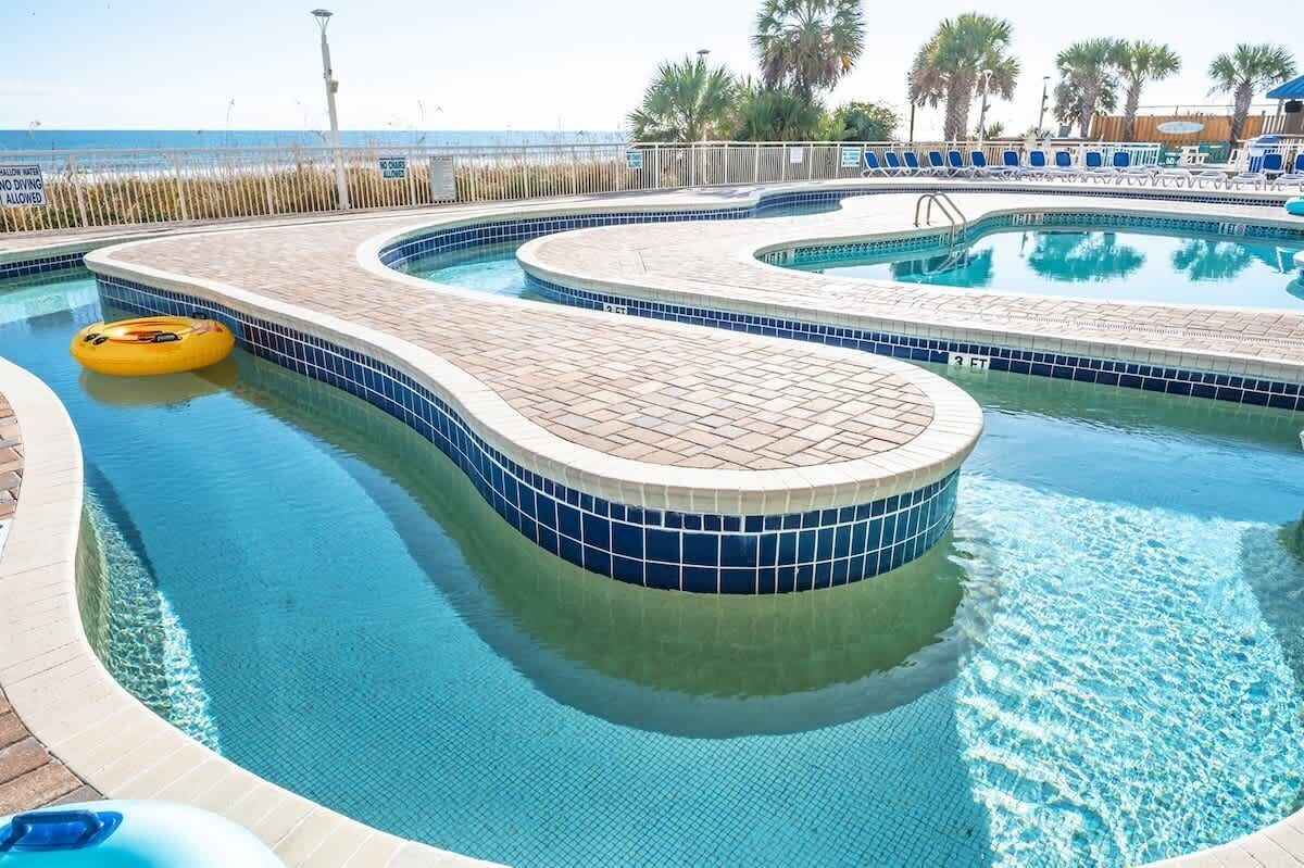 Une piscine au design incurvé, un poste de surveillance pour les sauveteurs et une vue sur la plage.