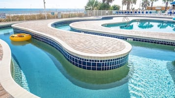 Une piscine au design incurvé, un poste de surveillance pour les sauveteurs et une vue sur la plage.