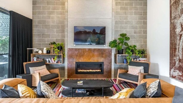 A modern living room with a fireplace, comfortable seating, and a large window. - Enjoy the deluxe swimming pool surrounded by a poolside sundeck (Lennox Head)