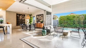 A modern interior with a dining area, kitchen, and a poolside seating area. - Enjoy the deluxe swimming pool surrounded by a poolside sundeck (Lennox Head)