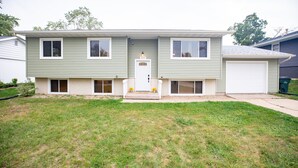 Ein zweistöckiges Haus mit Veranda, Garage und gepflegtem Rasen.