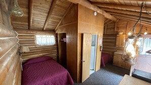 Une chambre confortable dans un chalet, avec un lit, un petit bureau, une armoire et une fenêtre avec des rideaux.