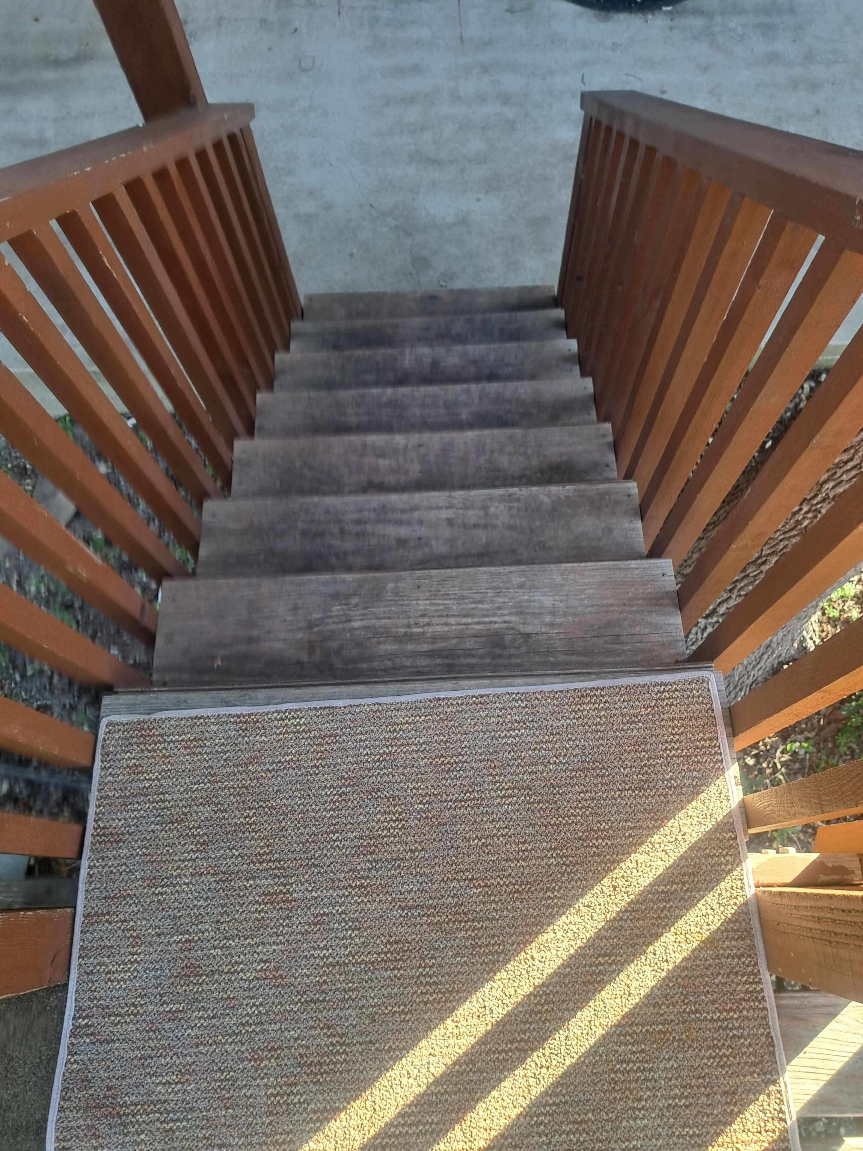 A wooden staircase with a textured carpeted landing.