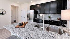 A modern kitchen with granite countertops, stainless steel appliances, and dark cabinetry.