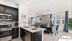 A modern kitchen with dark cabinetry, stainless steel appliances, and a central island.