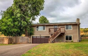 A two-story house with a garage, a wooden deck, and a staircase leading to the upper floor. - Hidden Valley Retreat. Foothill views. Large Yard! (Loveland)