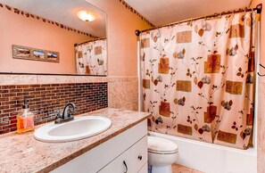 A bathroom with a sink, mirror, and shower curtain. - Hidden Valley Retreat. Foothill views. Large Yard! (Loveland)