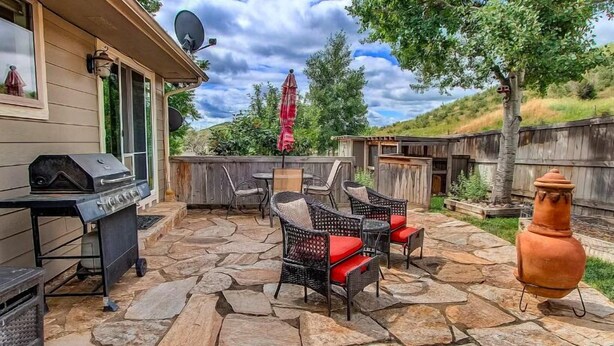 An outdoor patio with stone flooring, wicker furniture, a barbecue grill, and a decorative fire hydrant. - Hidden Valley Retreat. Foothill views. Large Yard! (Loveland)