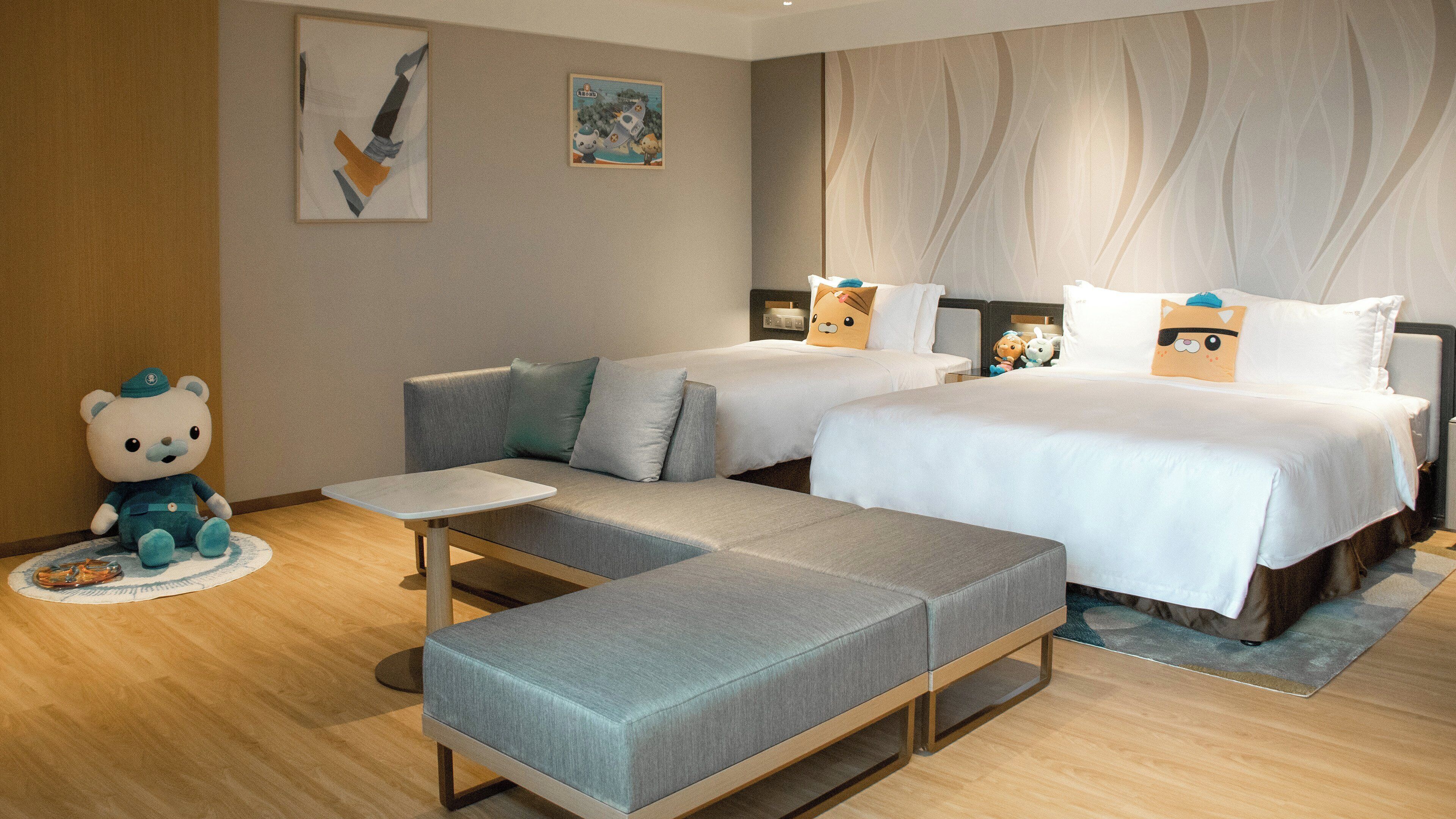 A hotel room with a sofa, a bed, a small table, and a bear decoration.