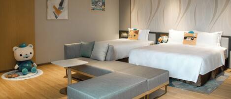 A hotel room with a sofa, a bed, a small table, and a bear decoration.