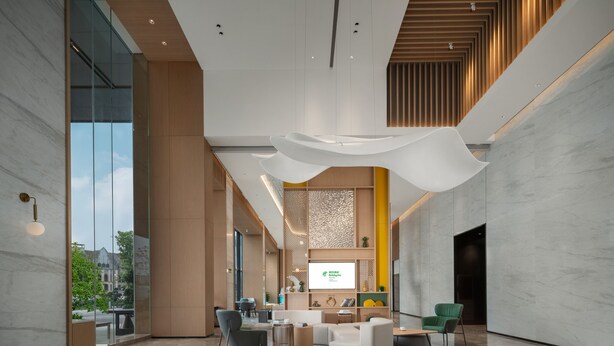 A spacious lobby with a modern design, featuring a large seating area, a reception desk, and a large screen displaying information. - Holiday Inn Luzhou Longjian by IHG (Luzhou)