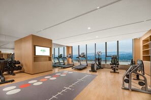 Ein modernes Fitnessstudio mit Laufbändern, Gewichten und einem großen Bildschirm, der ein Logo zeigt.