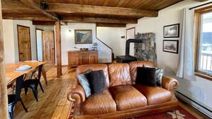 A cozy living room with a leather sofa, wooden dining table, and a stone fireplace. - Private Ranch Property Minutes to Yellowstone NP (Gardiner)