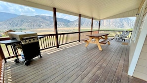 A covered outdoor deck with a grill, picnic table, and chairs, overlooking a mountainous landscape. - Private Ranch Property Minutes to Yellowstone NP (Gardiner)