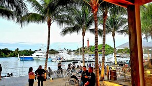 A marina with boats docked, palm trees, and people gathered at an outdoor seating area. - POSHPADZ Kai Villa-Water Views, Balcony, Walk to Jupiter Beach Sleeps 4 (Jupiter)