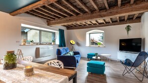 A cozy living room with a wooden ceiling, a sofa, a TV, and a dining area with a table and chairs. - Well-being house by the river (Cenans)
