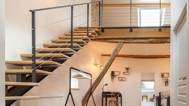 A modern interior with a wooden staircase, a desk, and a sofa in a bright, open space. - Well-being house by the river (Cenans)