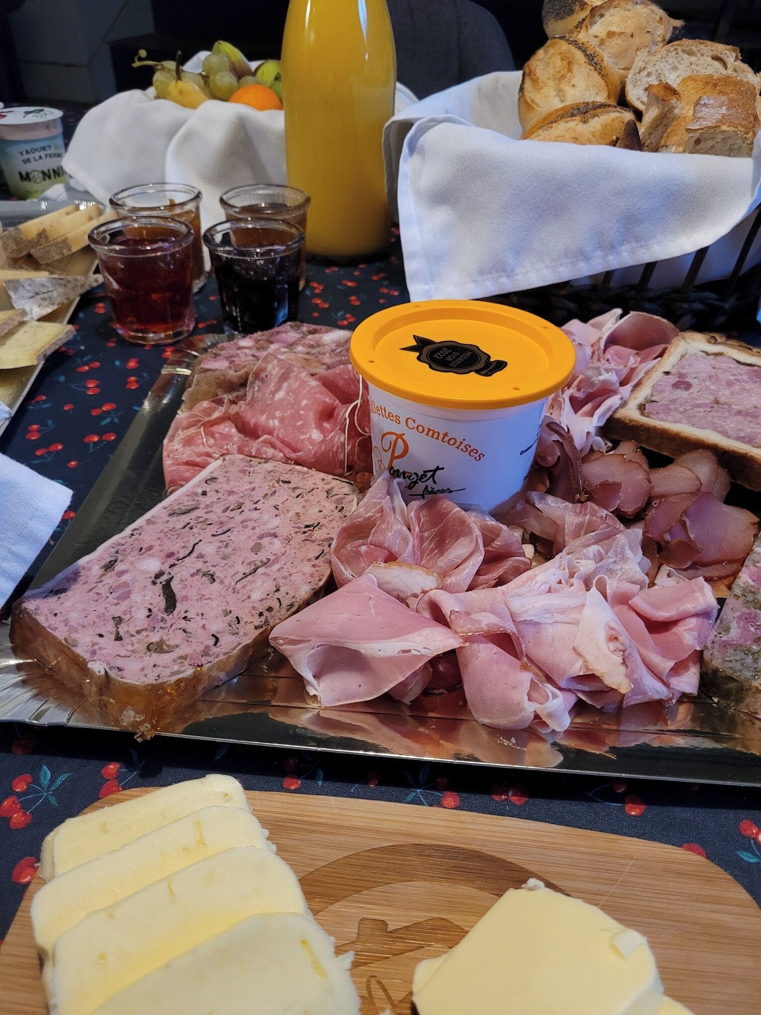 A charcuterie board with various meats, cheese, and a container of pâté.