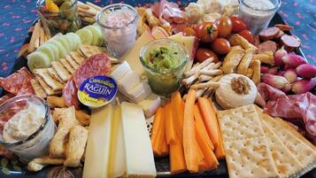 Un tagliere con formaggi, salumi, frutta e salse assortite.