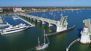 A marina with multiple boats, a bridge, and a lighthouse. - Beachy Getaway–Cozy, Clean & Equipped w/ All Essentials! Relax, Enjoy & Refresh! (St. Augustine Beach)