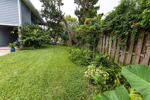 Um gramado bem cuidado com cerca de madeira e diversas plantas.