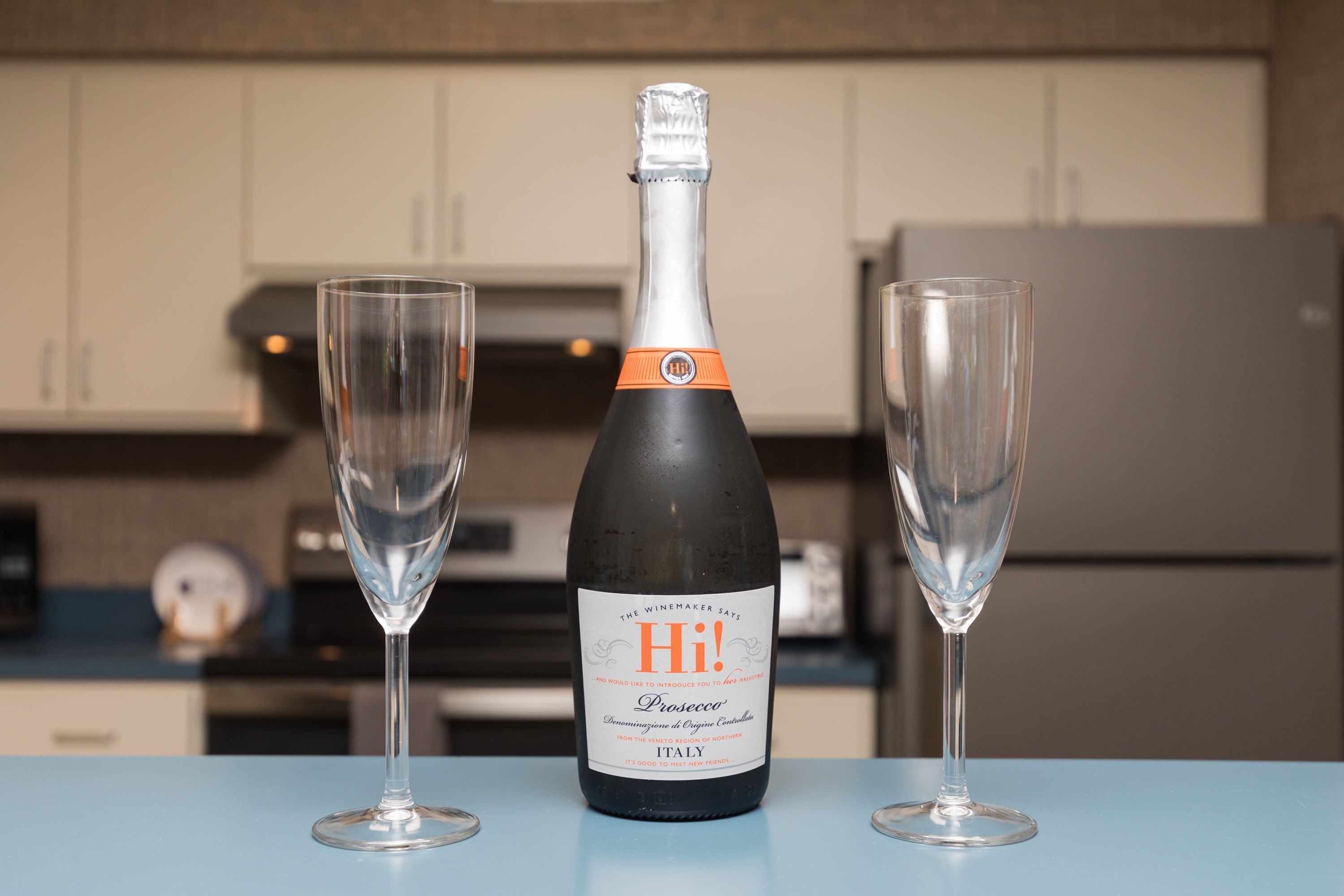 Una bottiglia di Prosecco e due bicchieri vuoti su un tavolo in cucina.