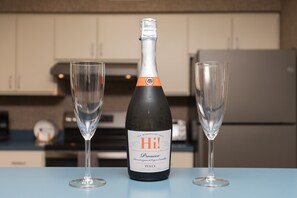 A bottle of Prosecco wine with two empty glasses on a table in a kitchen. - Beachy Getaway–Cozy, Clean & Equipped w/ All Essentials! Relax, Enjoy & Refresh! (St. Augustine Beach)