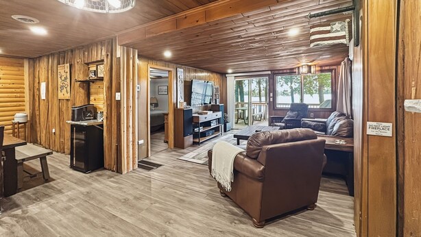 A log cabin interior with a living room, kitchen, and dining area.