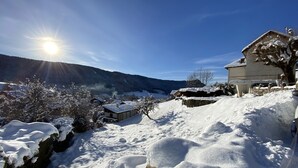 Paisaje nevado con una casa y una montaña al fondo.