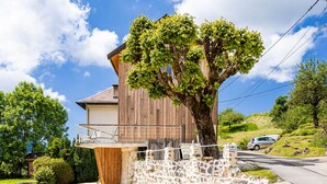 Un edificio rústico de madera con un muro de piedra y un árbol grande al frente.