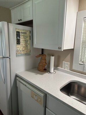 A kitchen with white cabinets, a wooden duck decoration, a map, and a stainless steel sink.