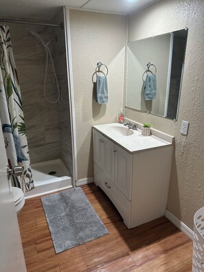 A bathroom with a shower, a sink, a mirror, and a toilet. - River Retreats/Anglers Paradise (Dunnellon)