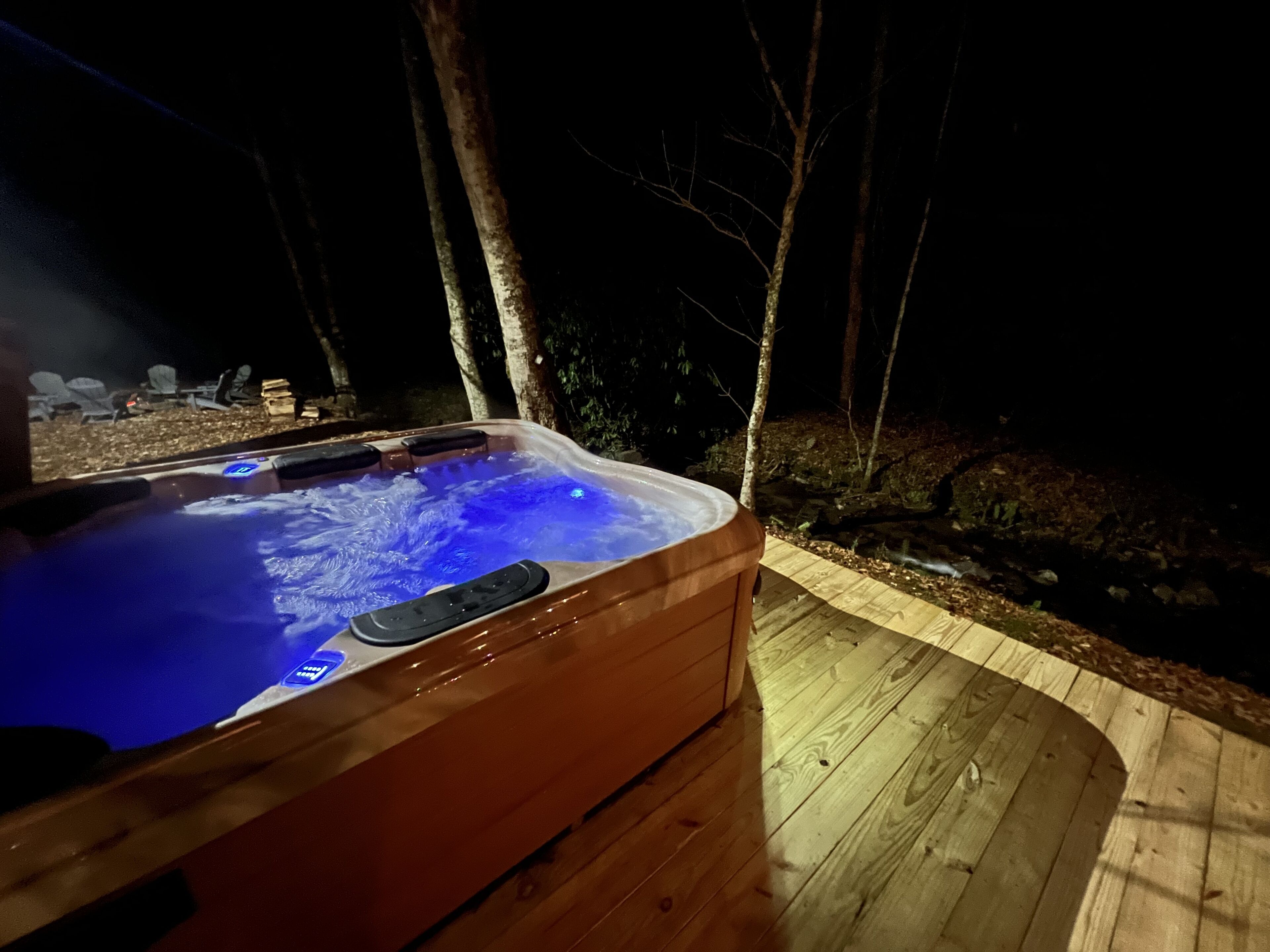 A hot tub with a wooden deck and a wooden fence in the background.