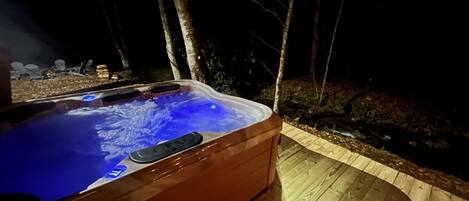 A hot tub with a wooden deck and a wooden fence in the background.