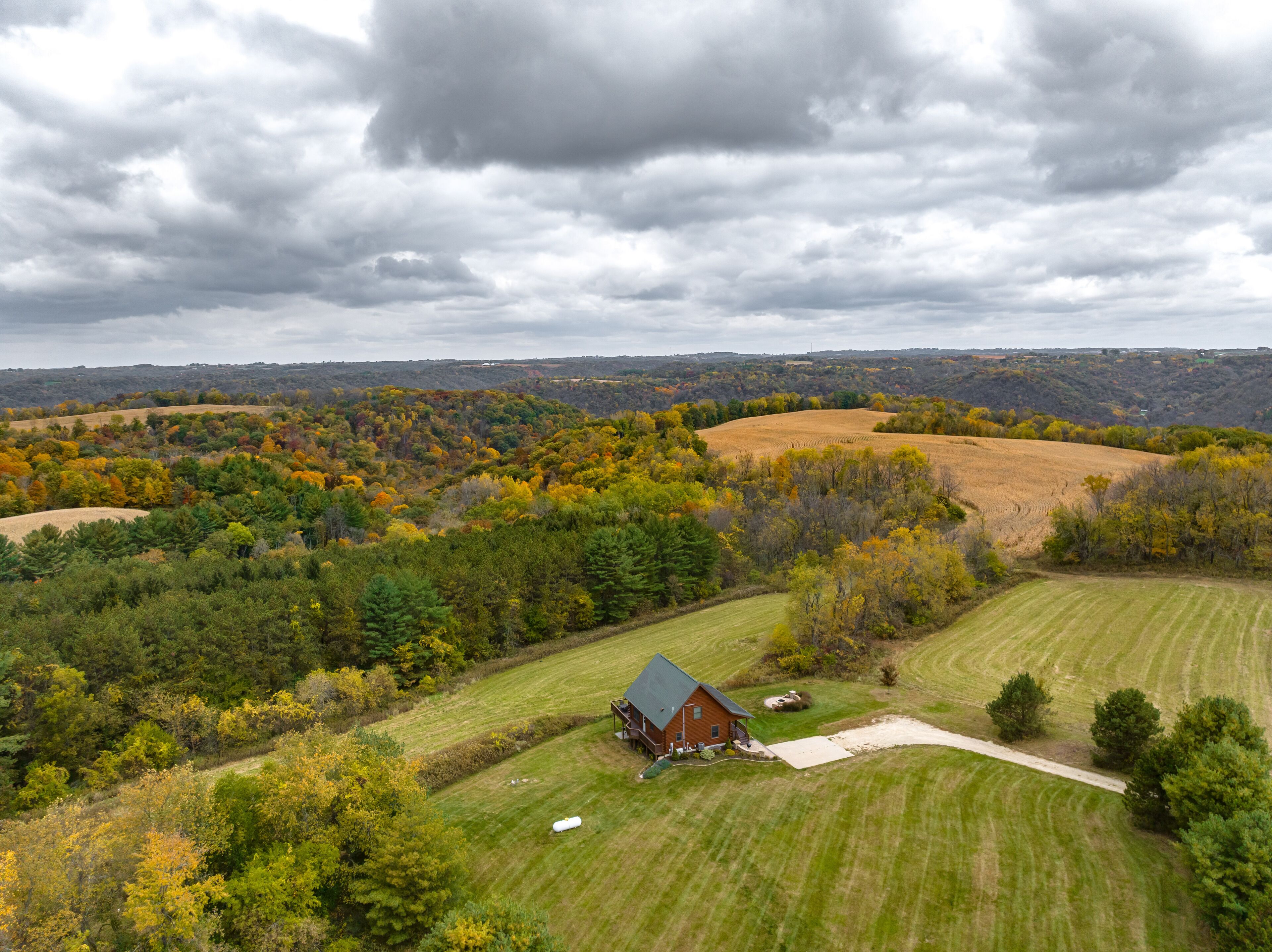 A rural landscape with a house surrounded by fields and trees.