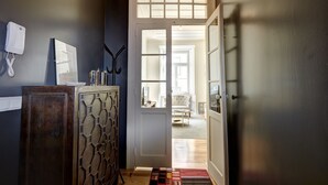 A hallway with a wooden cabinet, a telephone, and a door leading to a living area with a sofa and a coffee table. - Downtown Historic Center - Air Conditioning/Elevator (Lisboa)