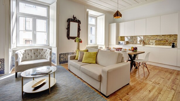 A modern living room with a sofa, coffee table, and a dining area with a table and chairs. - Downtown Historic Center - Air Conditioning/Elevator (Lisboa)