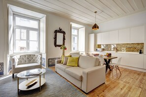 A modern living room with a sofa, coffee table, and a dining area with a table and chairs. - Historic City Center - Air Conditioning/Elevator (Lisboa)