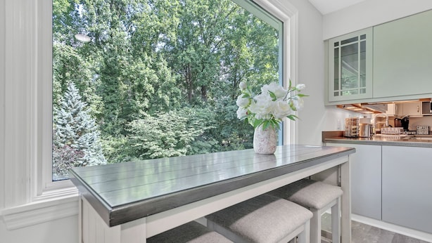 A kitchen with a large window, a vase with flowers, and a countertop.